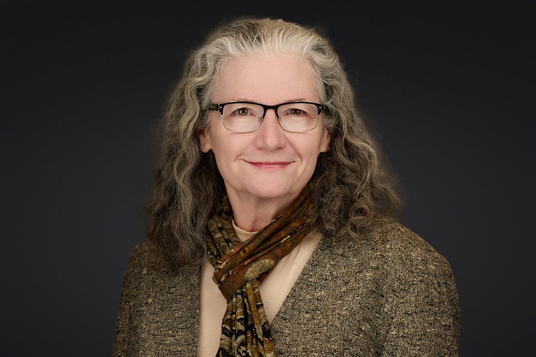 LinkedIn headshot of a woman with glasses and a scarf, photographed on location in Maryland